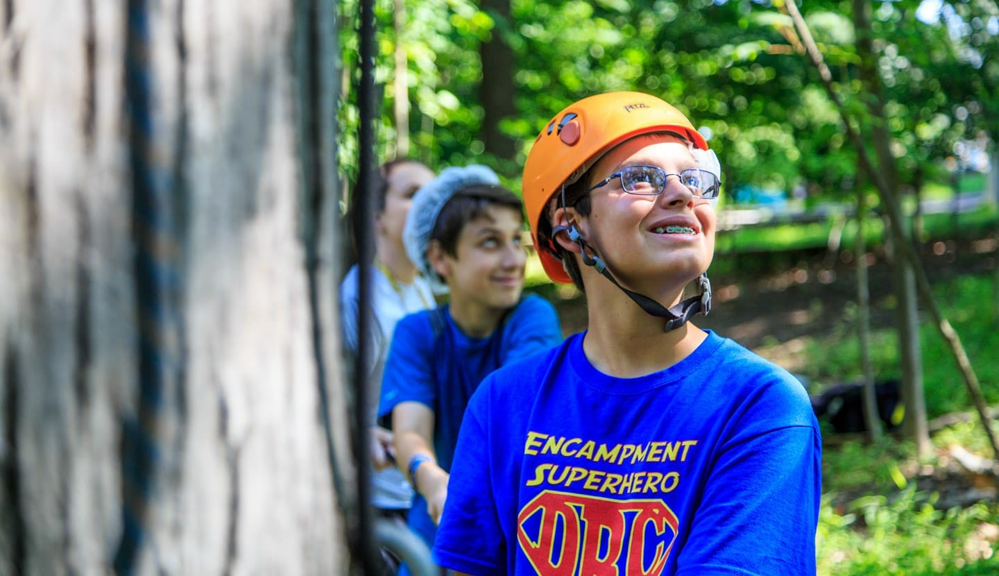 Male camper wearing helmet by ropes course